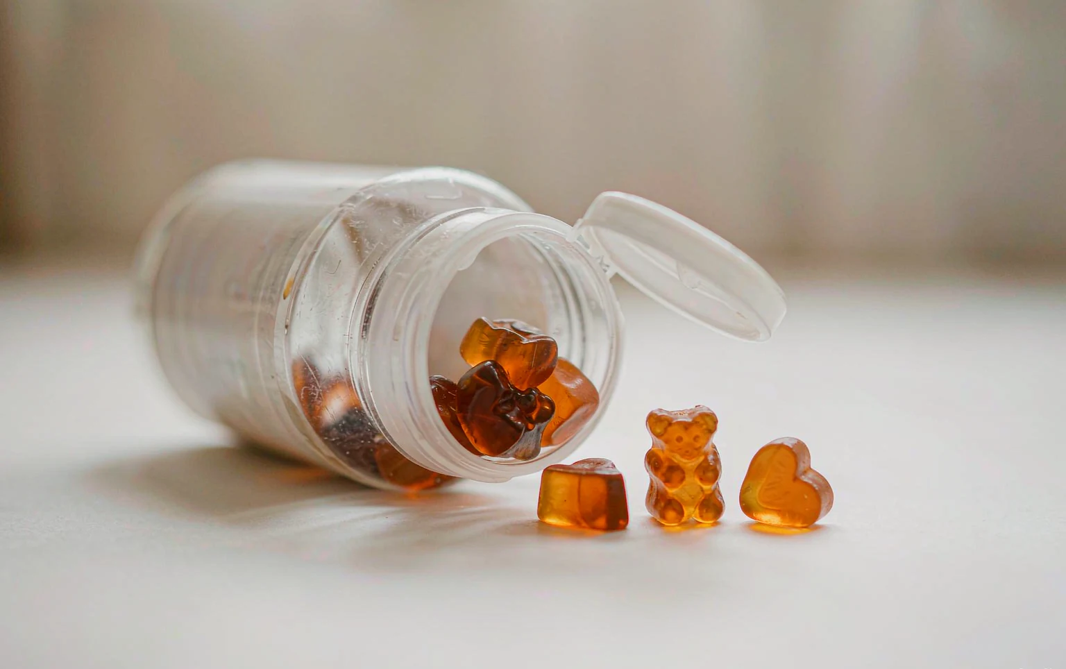 Open vitamin bottle with gummy vitamins fused into a single sticky clump at the bottom
